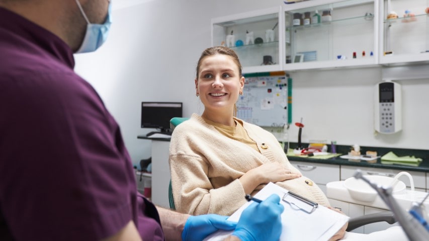 Pregnant woman listens to endodontist explain root canal procedure.