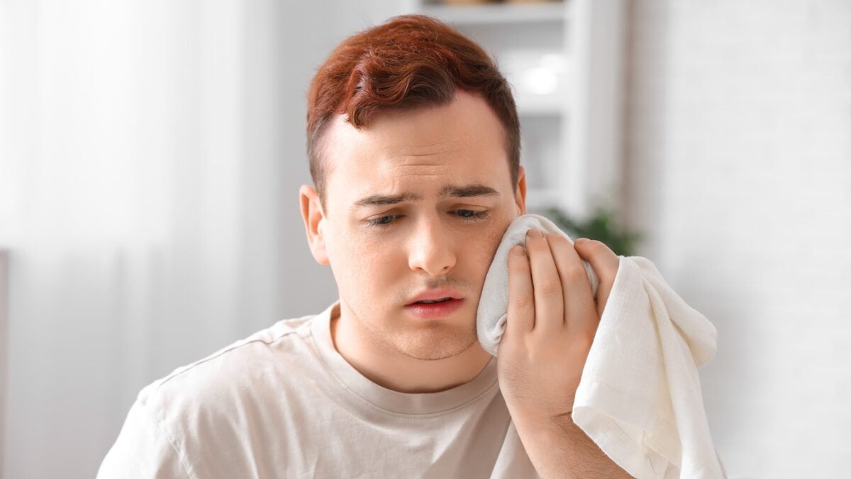 Man using an ice pack to manage tooth pain.