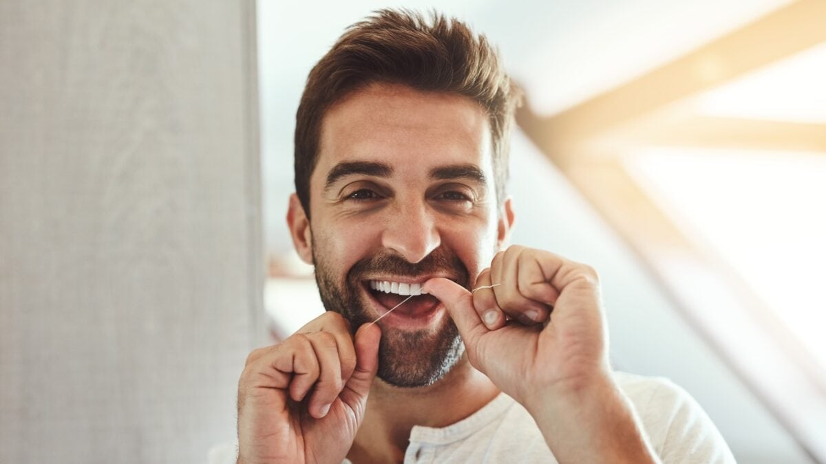 Man flossing his teeth to prevent tooth infection.