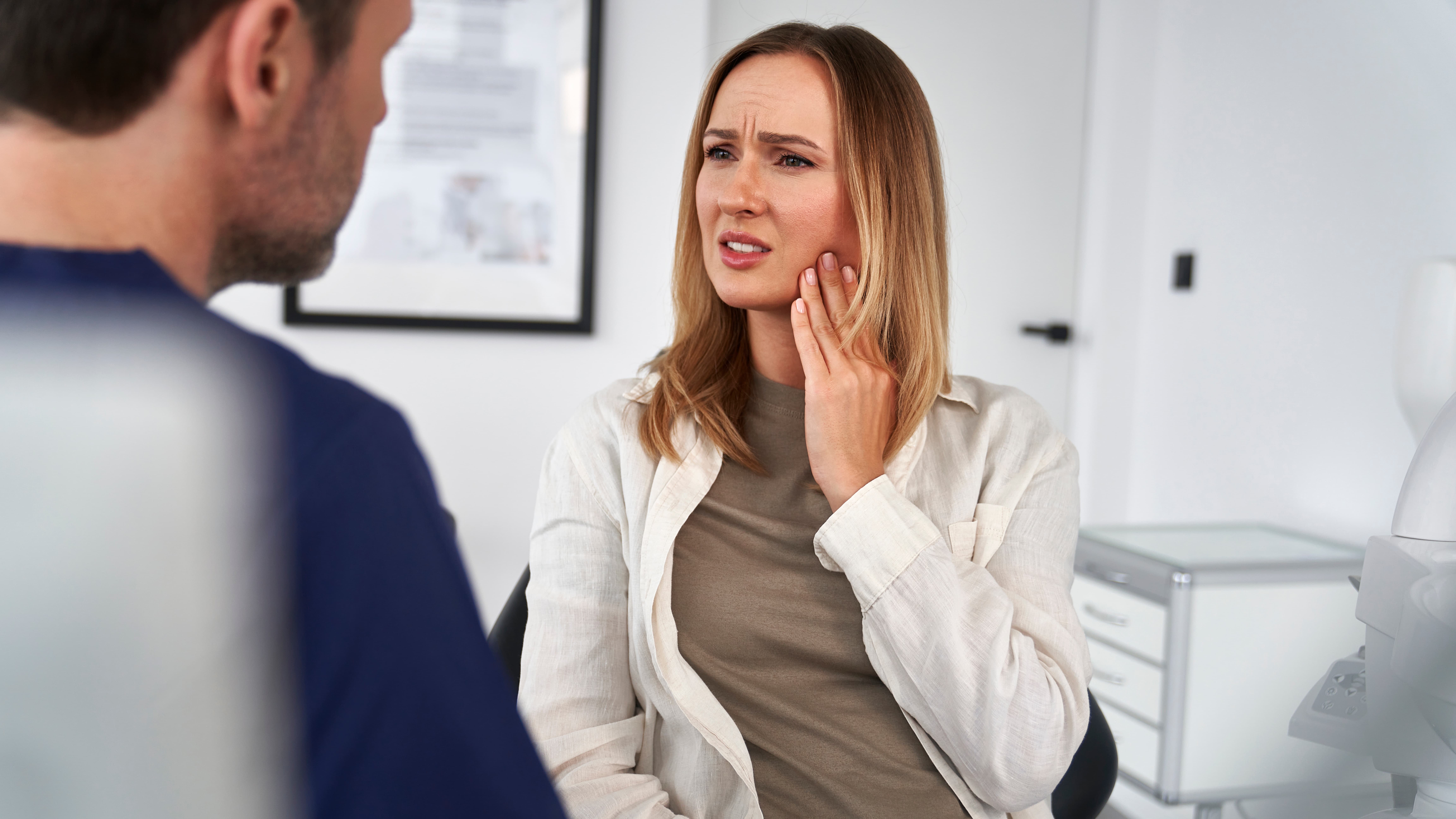 Female patient describing toothache to a dentist.